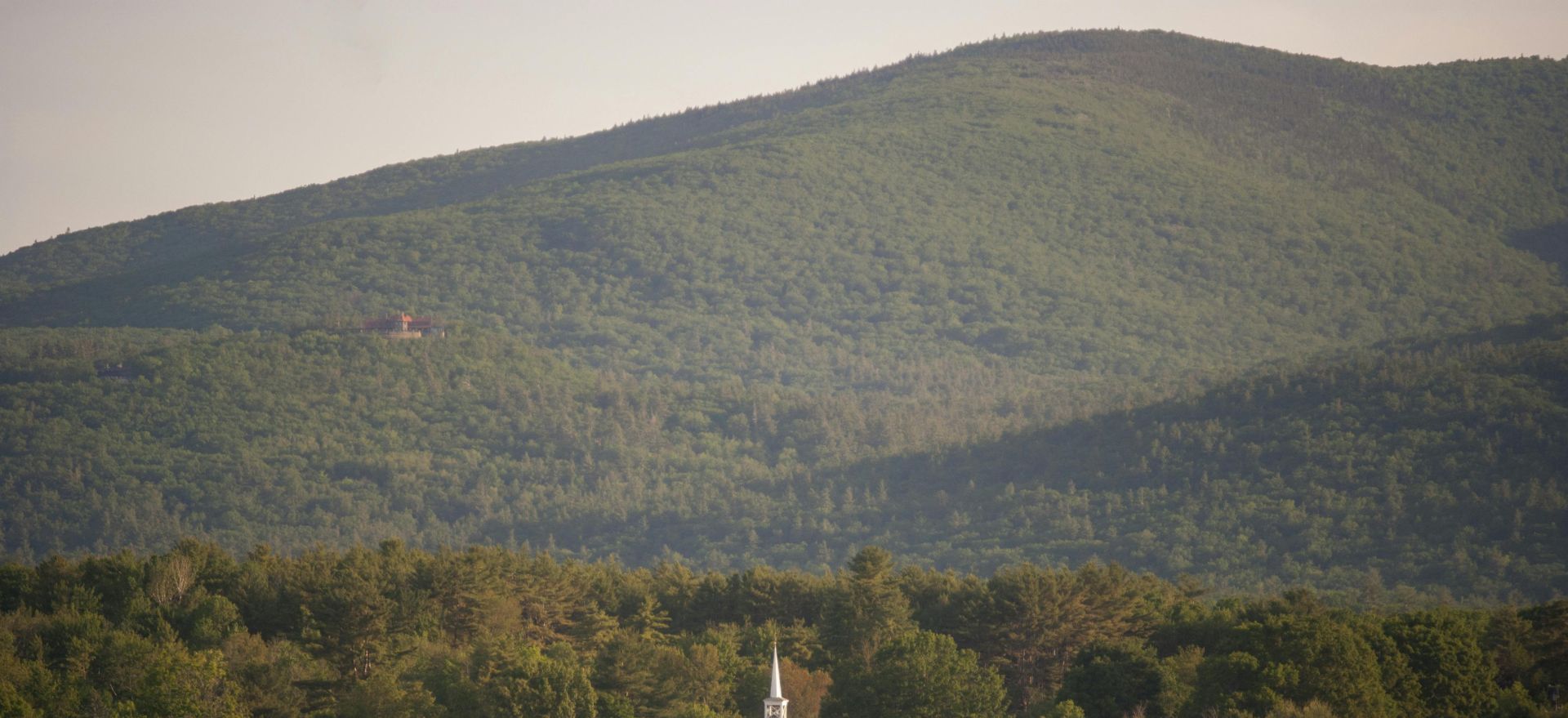 Picturesque church by a lake with mountain backdrop in Tuftonboro, New Hampshire.